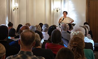 Judith Schalansky steht an einem Stehpult und liest, im Vordergrund Publikum