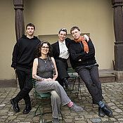 Vier junge Menschen sitzen und stehen nebeneinander im Innenhof des Museums.